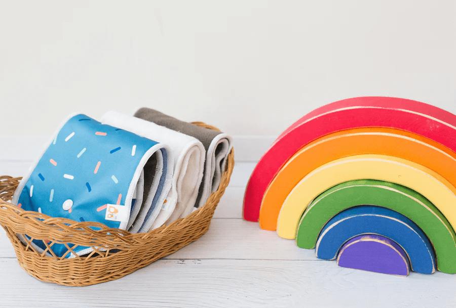 reusable diaper inserts in a basket next to a rainbow