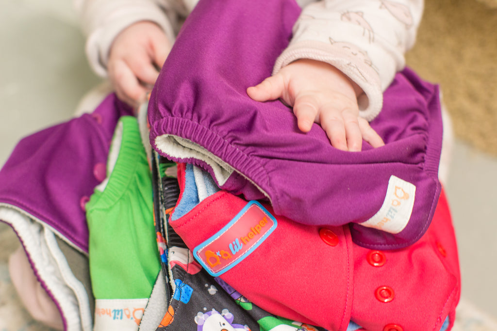 Baby holding five cloth diapers