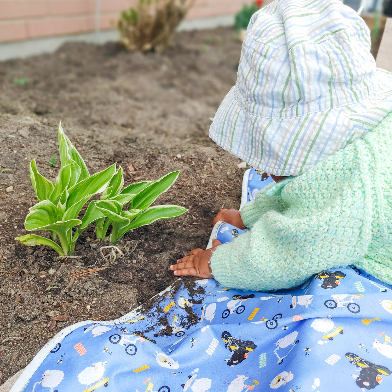 baby laying on a reusable mat while playing with a plant